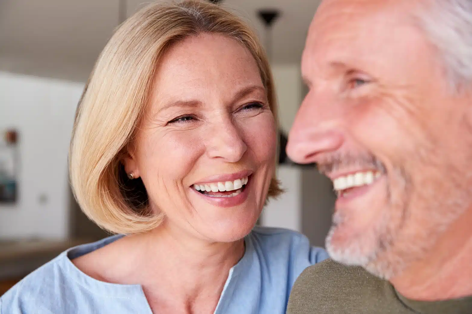 Smiling older couple sitting close together, laughing and enjoying time together at home