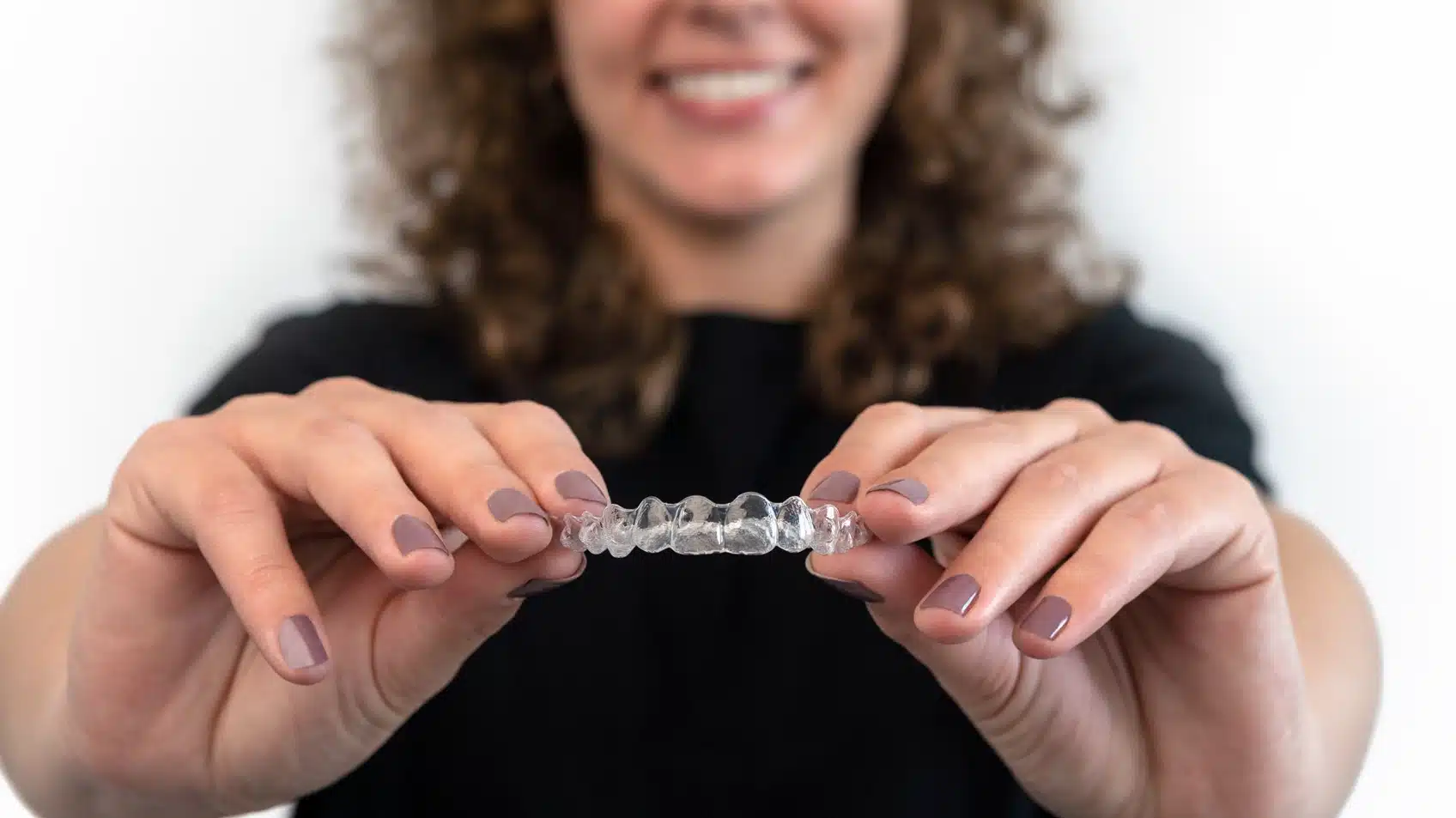 Woman holding a clear dental aligner