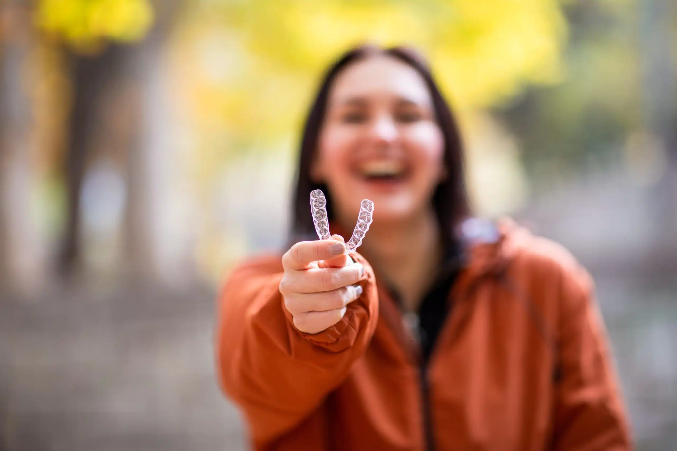 Woman holding a clear aligner while smiling