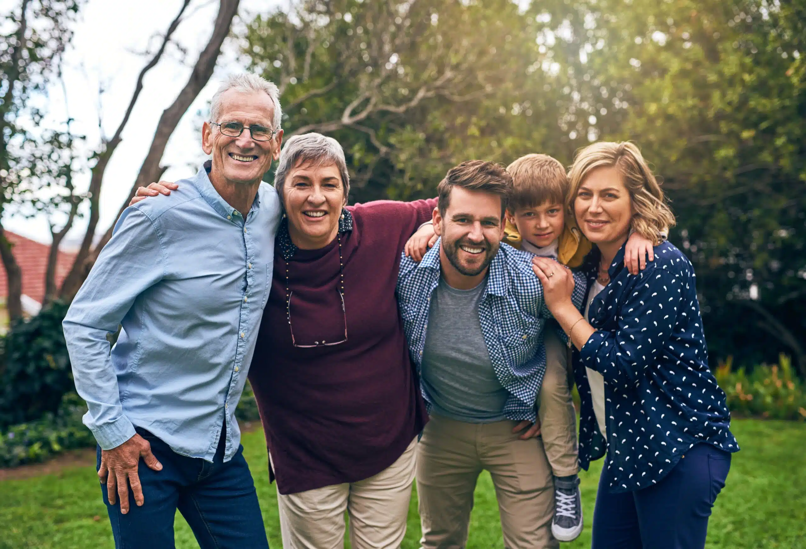 Smiling multigenerational family standing together outdoors and enjoying time together.